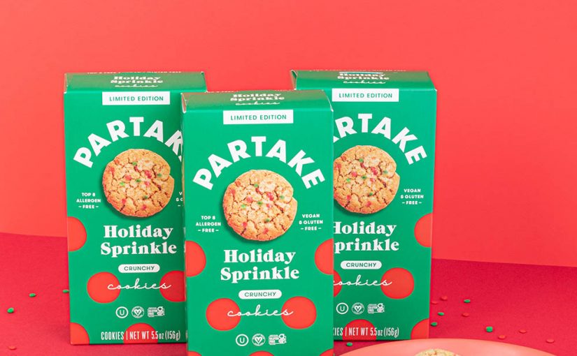 Partake Holiday Sprinkle cookies with green boxes sitting on a red table