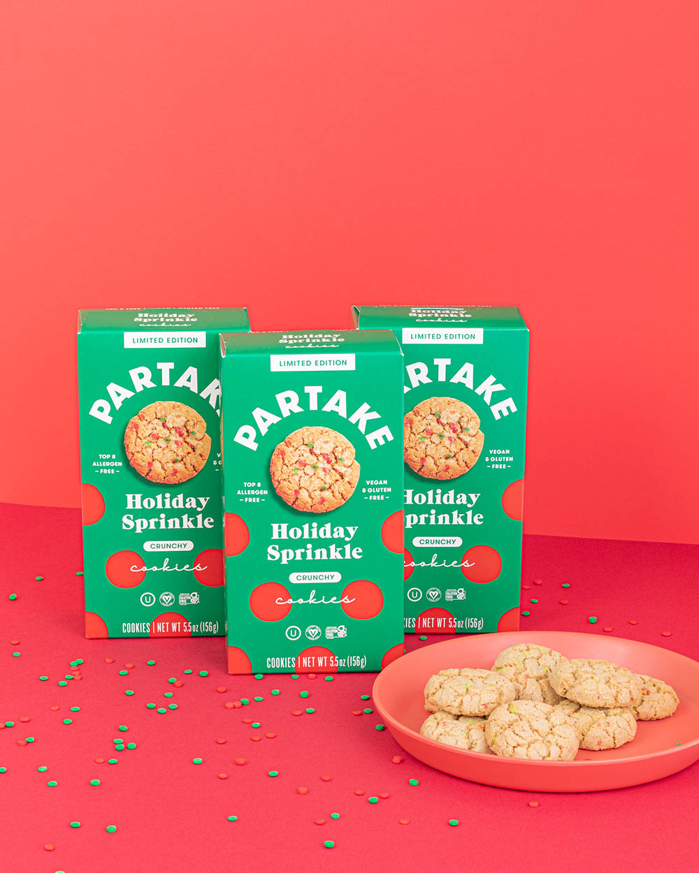 Partake Holiday Sprinkle cookies with green boxes sitting on a red table